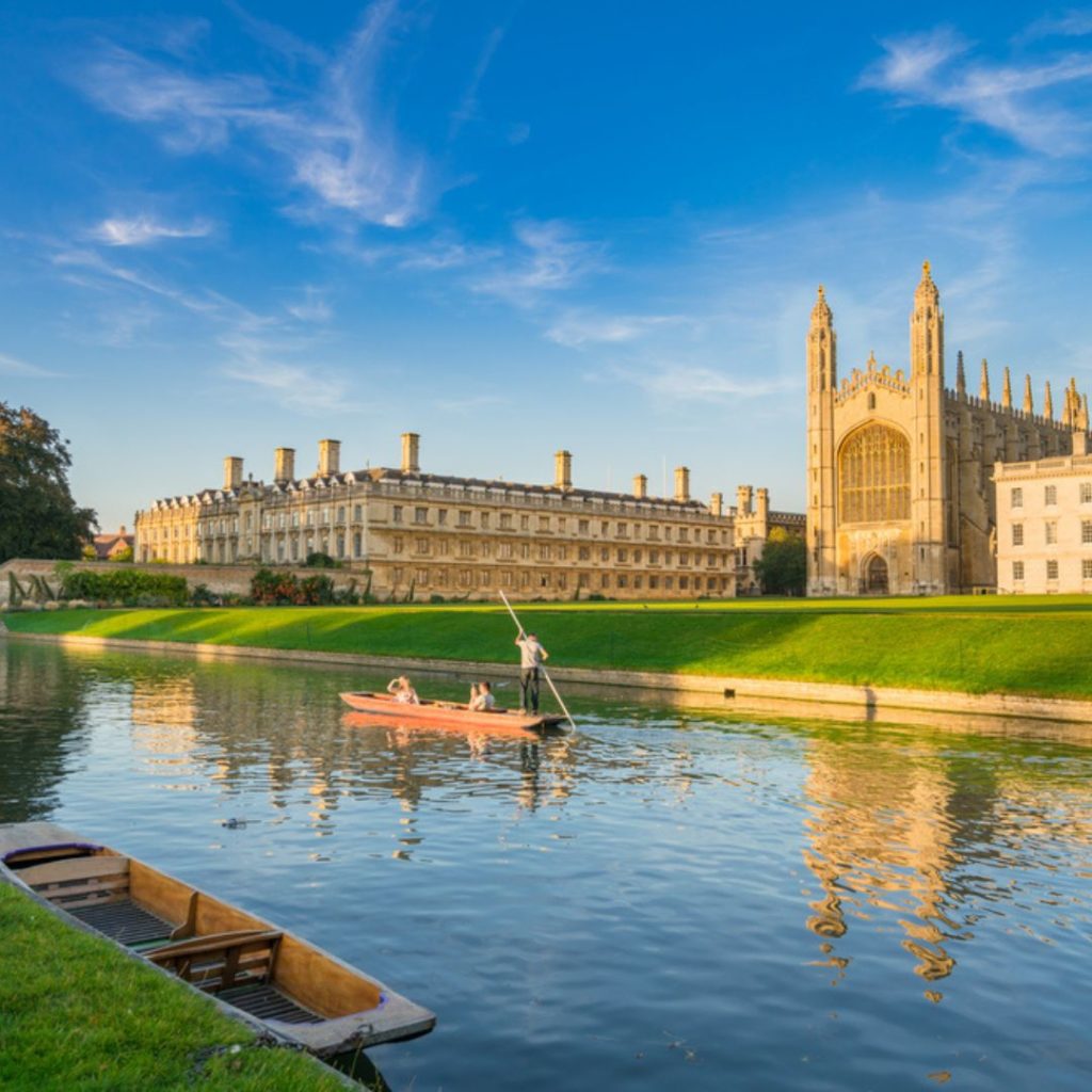 Cambridge university as seen from the river with a boat going past