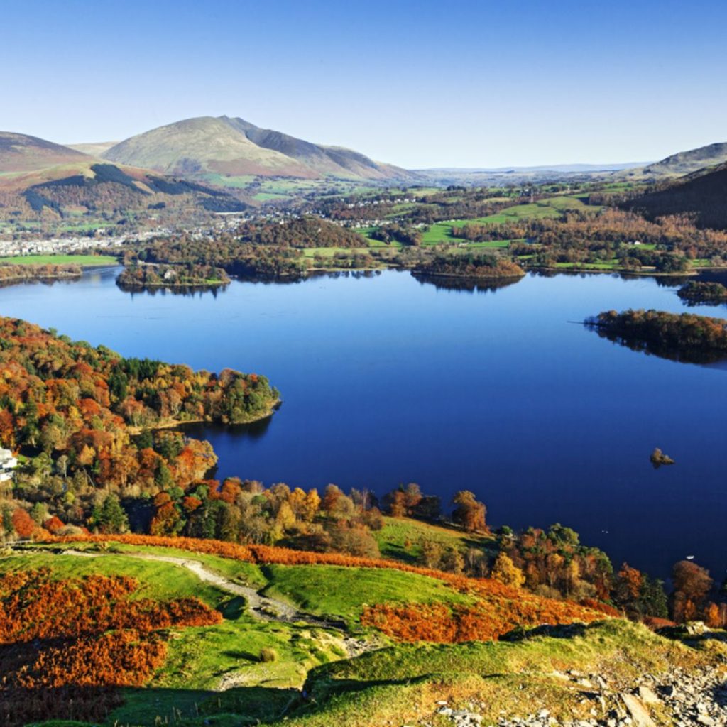 The lake district from above showing a lake surrounded by mountains. Visiting is one of the thigns to do in England