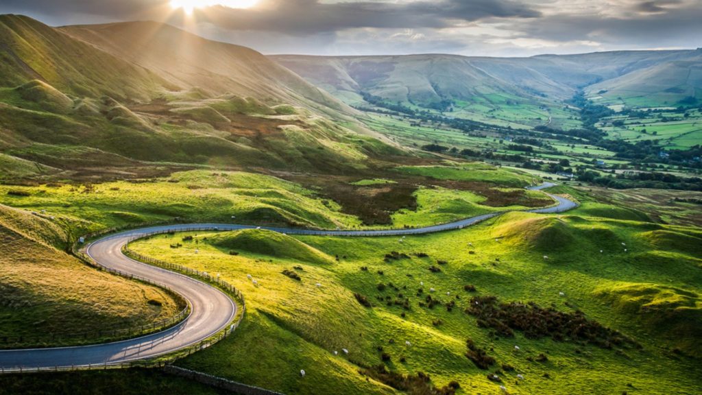 Mountains in The Peak Distict with a road running through visiting is one of the things to do in England