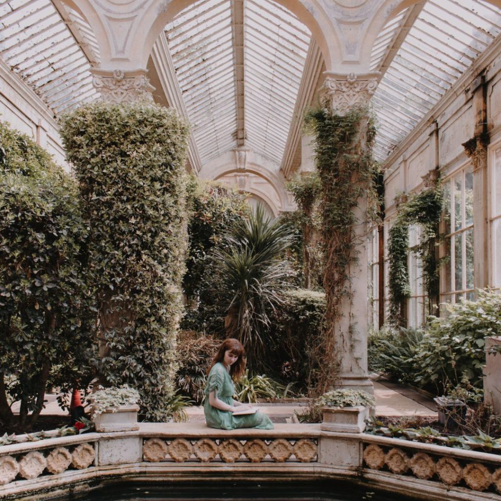 Girl sat beside a pond in a greenhouse at Castle Ashby Northamptonshire