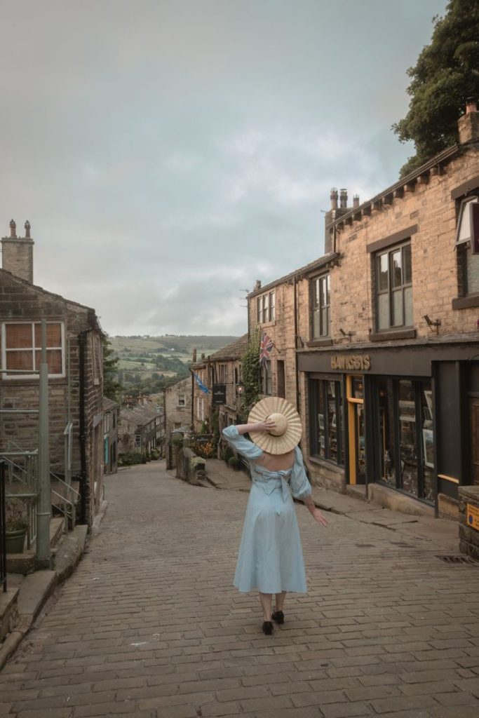 Girl with a hat on walking down a street in Haworth