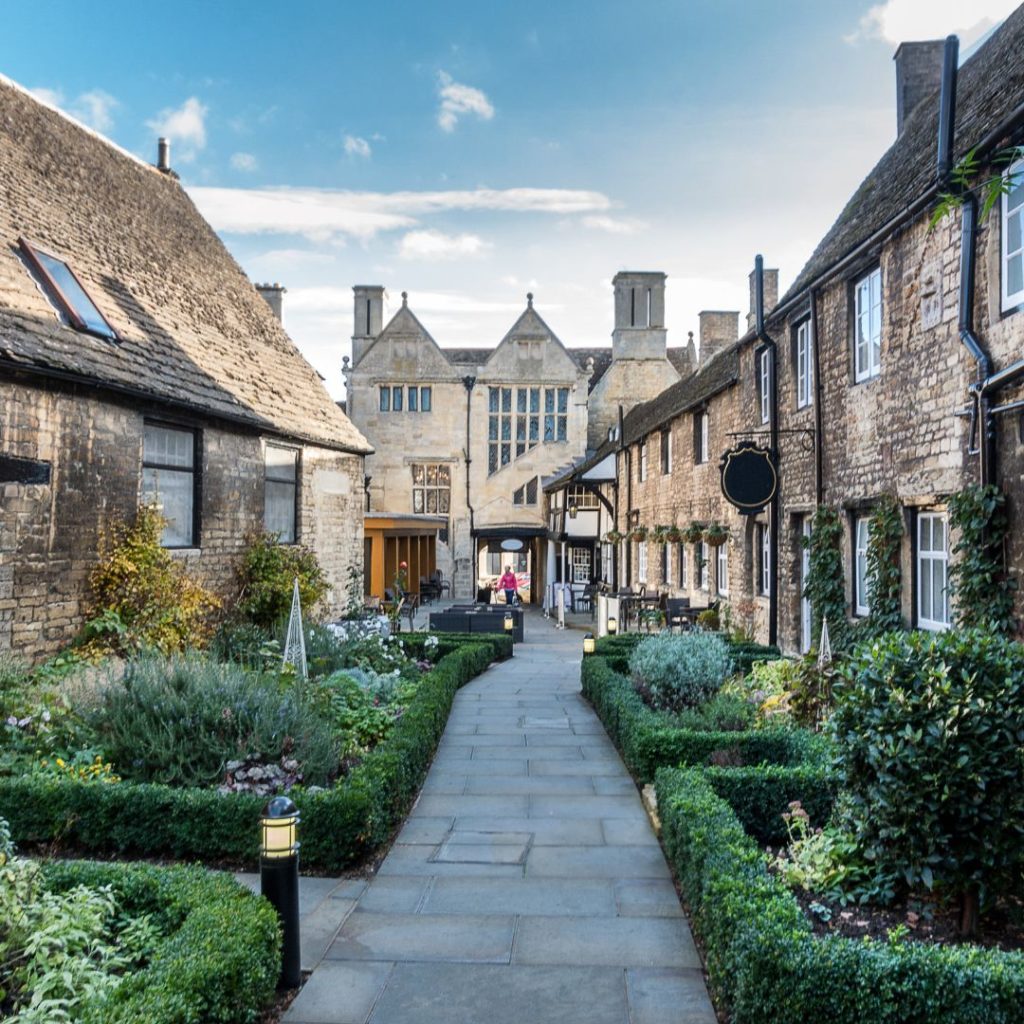 A line of houses with a walkway down the middle and hedges in front of the hedges